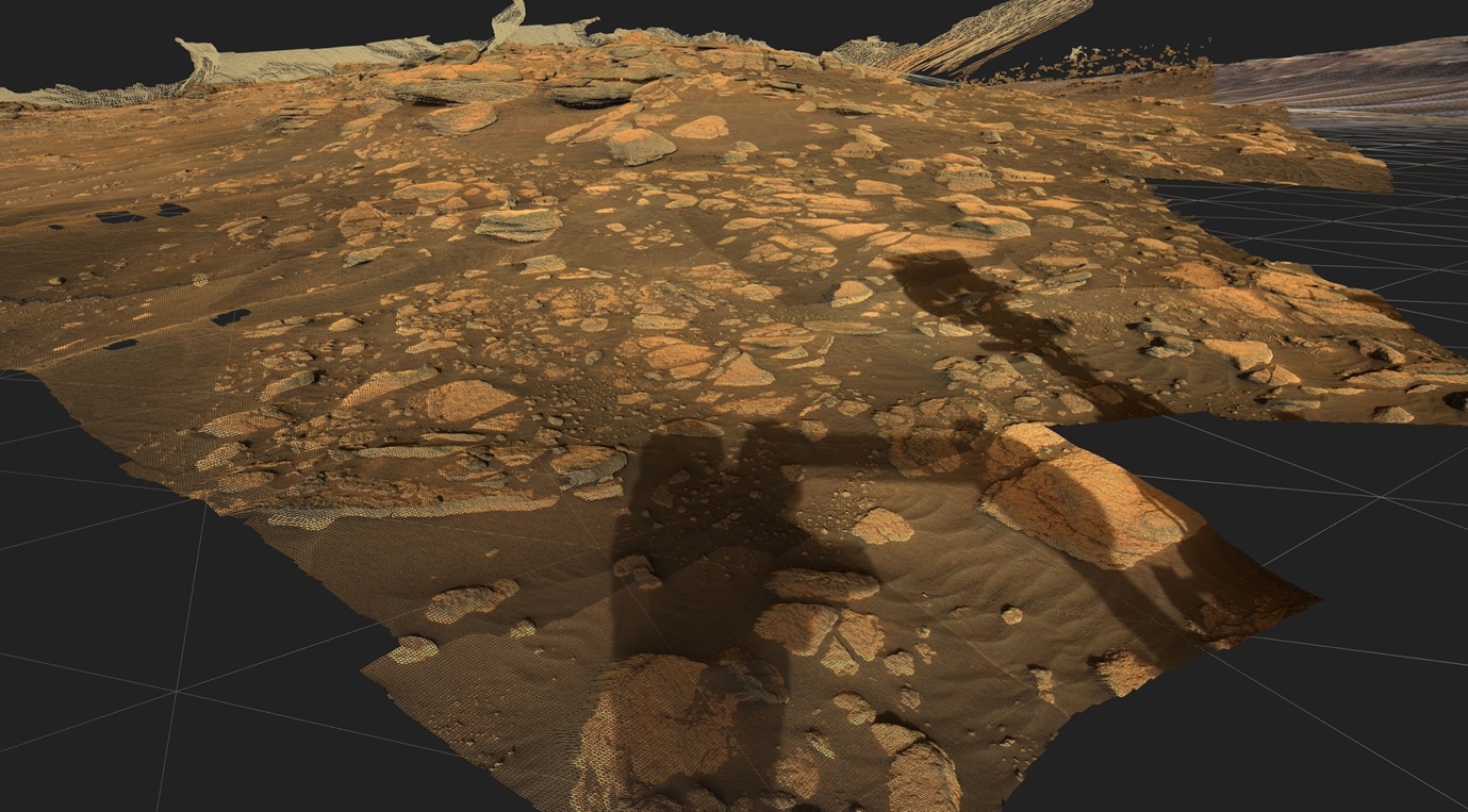 Zu sehen ist eine lose Gesteinsformation aus einer Rekonstruktion der Marsoberfläche in braunen Farben sowie der Schatten des Mars-Rovers Perseverance, welcher die Aufnahmen getätigt hat.