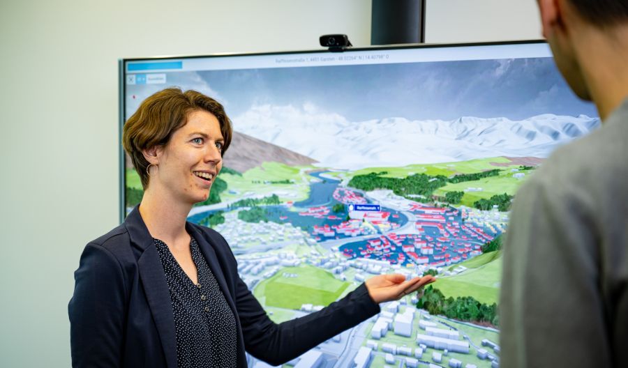 VRVis researcher Silvana Rauer-Zechmeister points to a large screen on which a flood simulation can be seen.