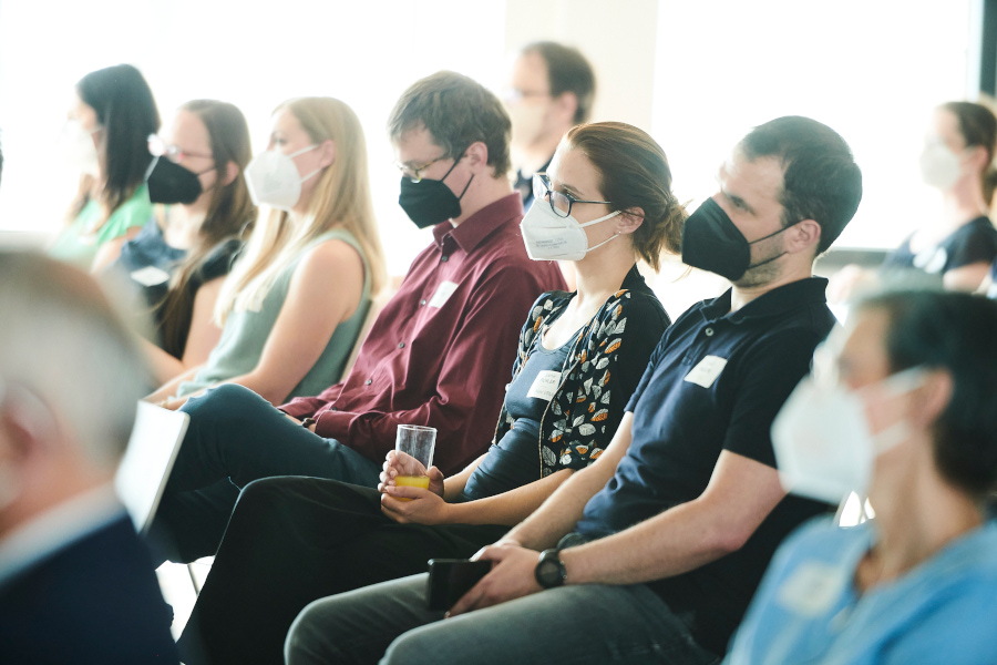 View of the audience at a panel discussion, the women and men wearing protective masks.