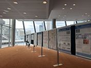 An exhibiton of posters in a room with large glass windows