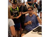 A researcher with glasses surrounded by children and young people. 