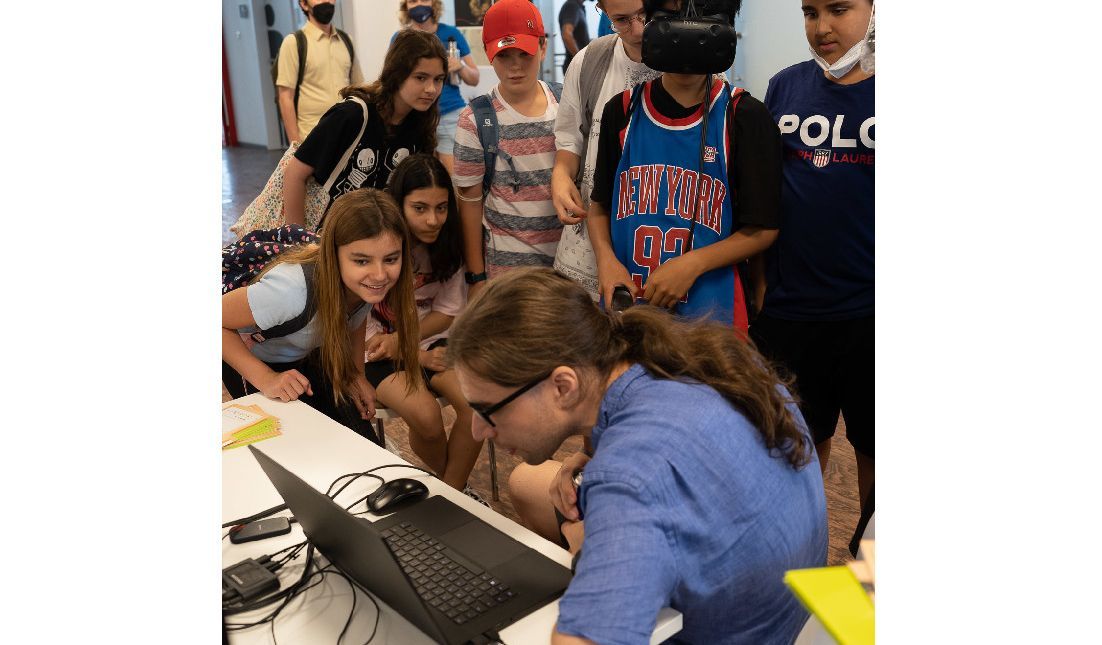 A researcher with many young people around a laptop. 