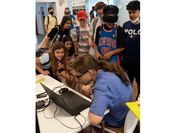 Ein Forscher mit vielen Jugendlichen um einen Laptop. 