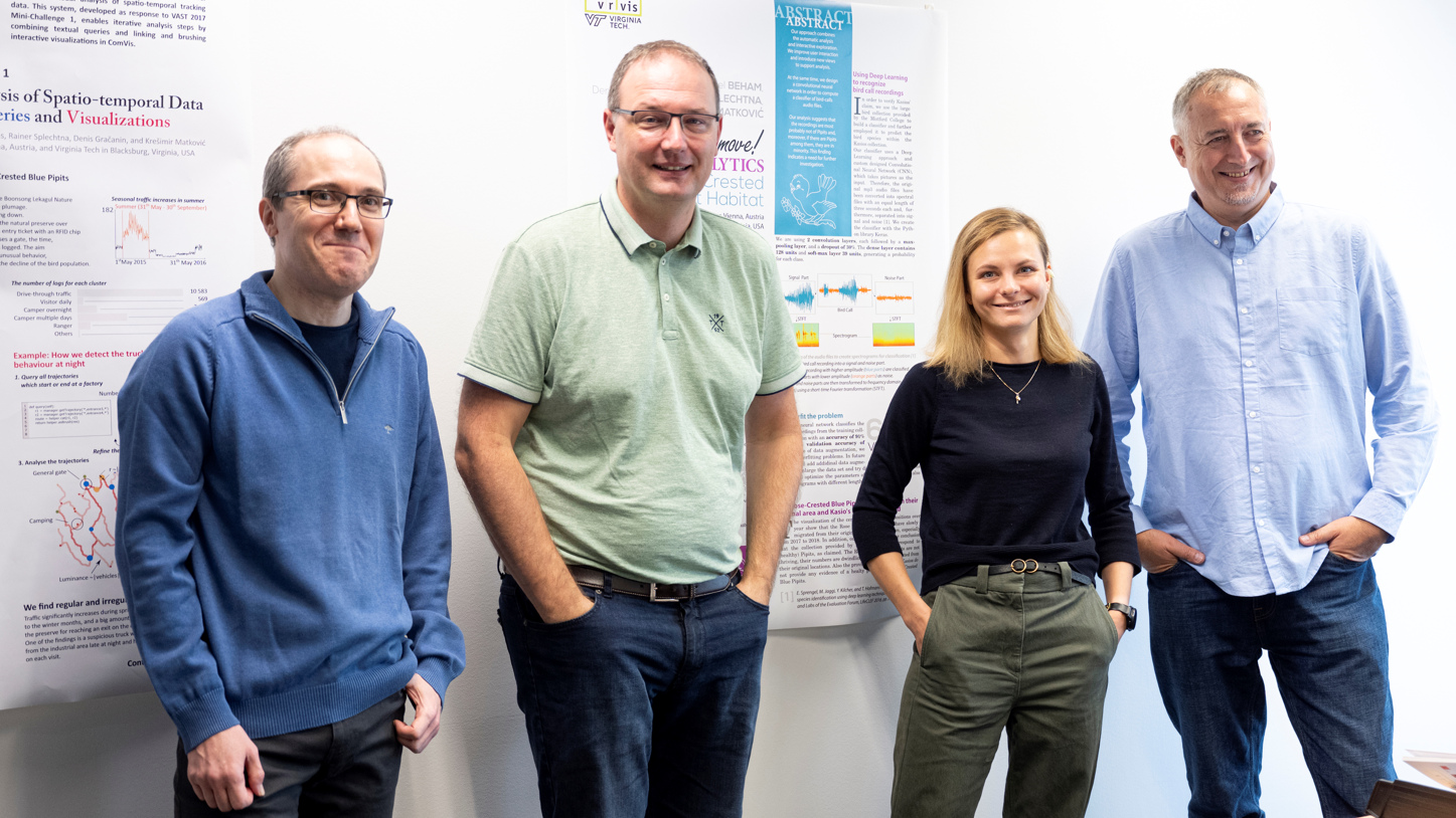 Three researchers and a female researcher of the Interactive Visualizations Group at VRVis in front of two posters presented at scientific conferences. 