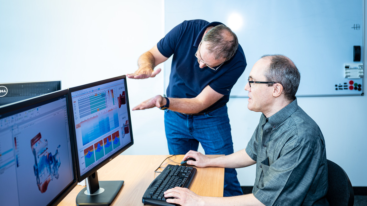 Zwei Forscher besprechen etwas vor zwei Computerbildschirmen. 