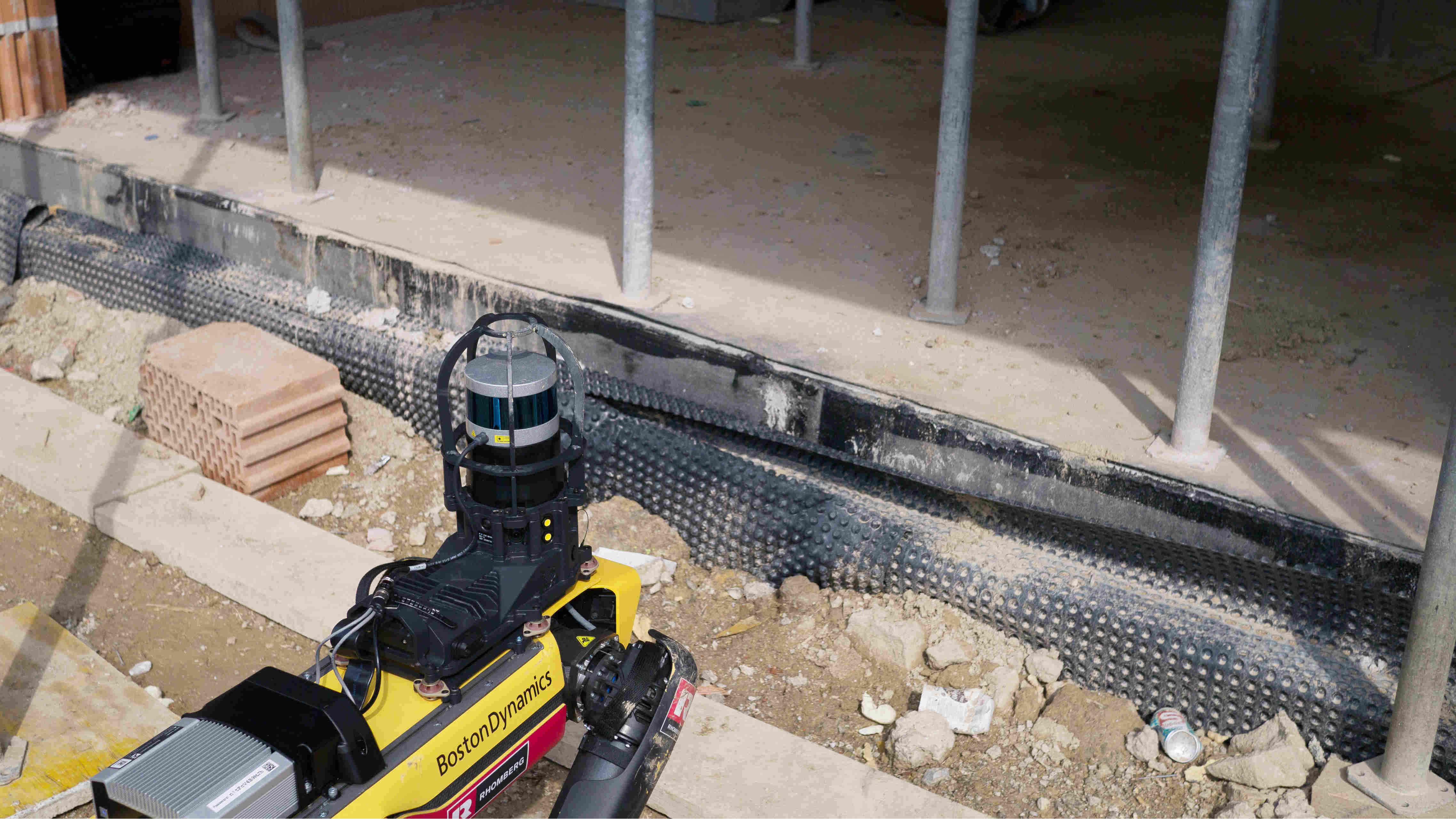 Boston Dynamics-Roboterhund Spot beim Einsatz auf der Baustelle mit Blick auf eine Reihe von Gebäudestützen. 