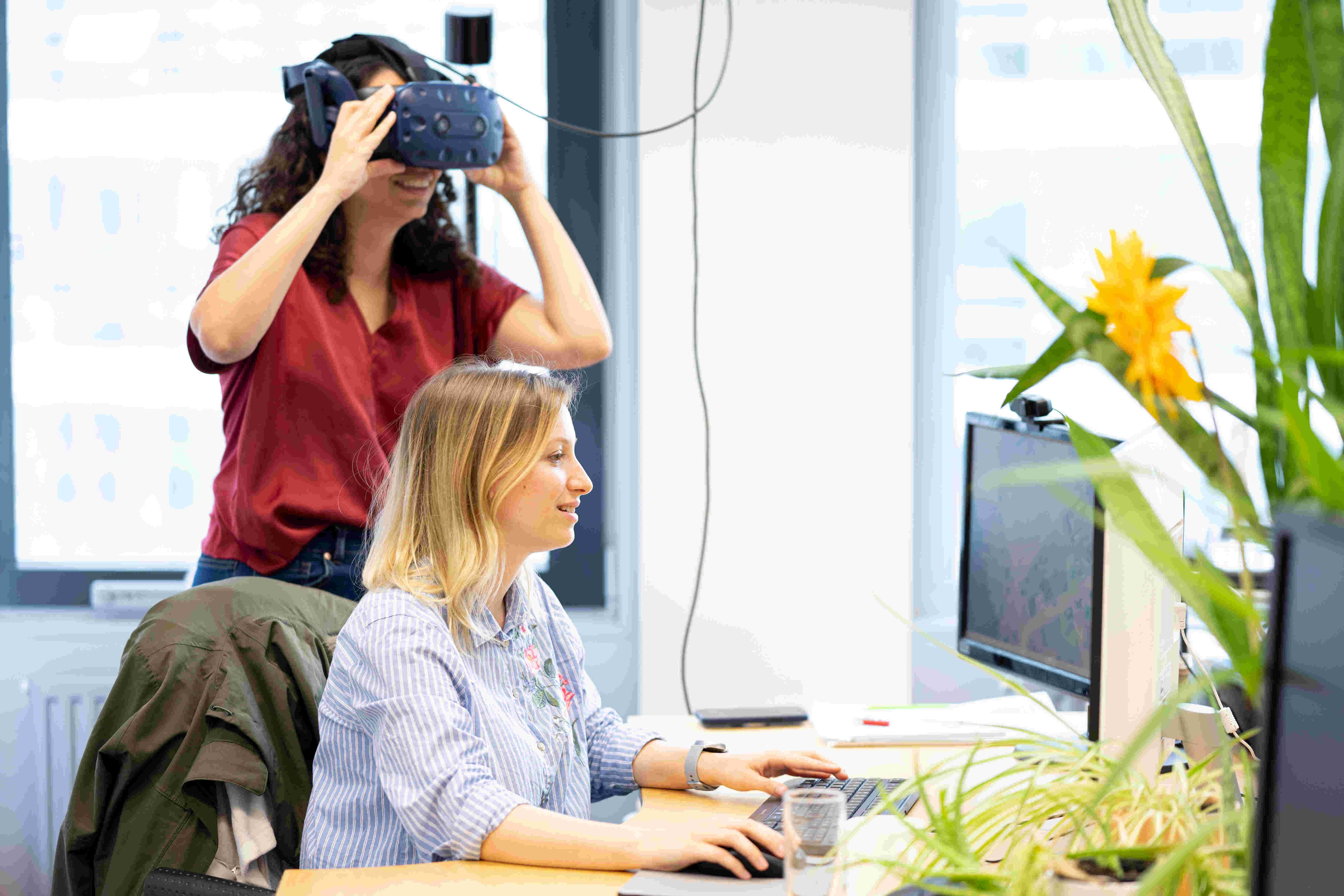 Eine Forscherin mit VR-Brille und eine Forscherin vor dem Monitor testen die VR-Anwendung des VRVis für die Motorenentwicklung