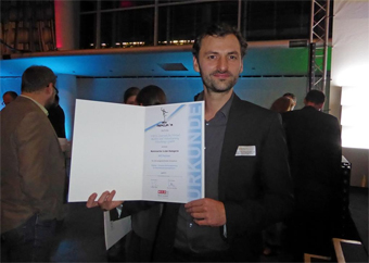 Der Forscher Jürgen Waser hält die Urkunde des Mercur-Innovationspreis in die Kamera.