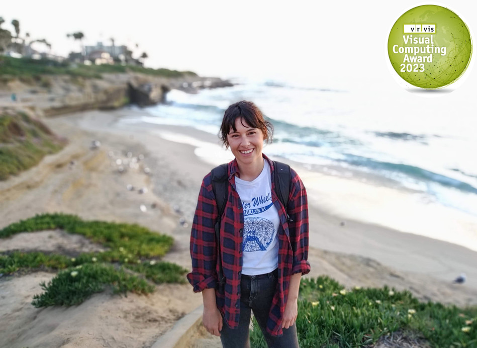 Gaia Pavoni, die an einem Strand steht, der unscharf im Hintergrund zu sehen ist, lächelt in die Kamera.