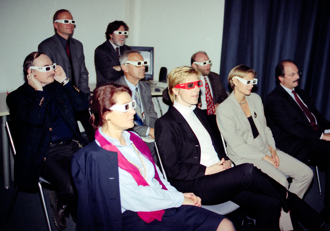 Mehrere Menschen sitzen in einem Raum und haben 3D-Brillen auf und folgen einer Technologie-emo.
