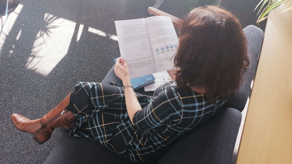 Forscherin Johanna Schmidt sitzt ein Paper lesend auf einer Couch.