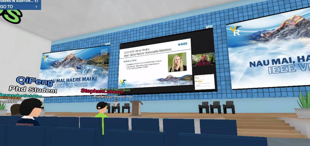 Screenshot from the Virbela virtual environment: conference room with avatars and presentation screens. 