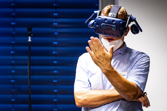 A man wears virtual reality gear and holds his hand in front of his face.