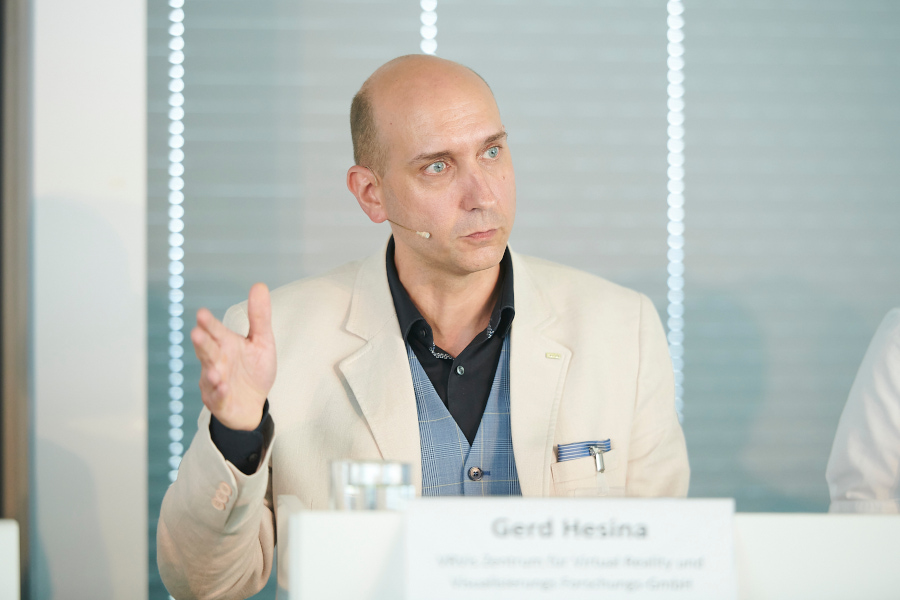 Gerd Hesina sitzt auf einem Podium und spricht über Visual Computing und Green Tech.