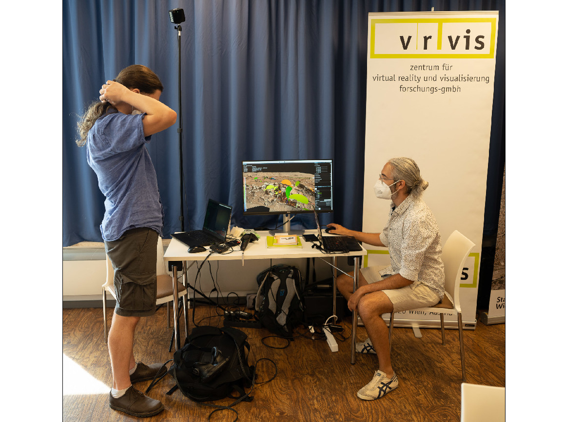 Zwei Forscher um einen Computerbildschirm, auf den bunte Kreise auf der Marsoberfläche zu sehen sind. Plus VRVis-Banner. 