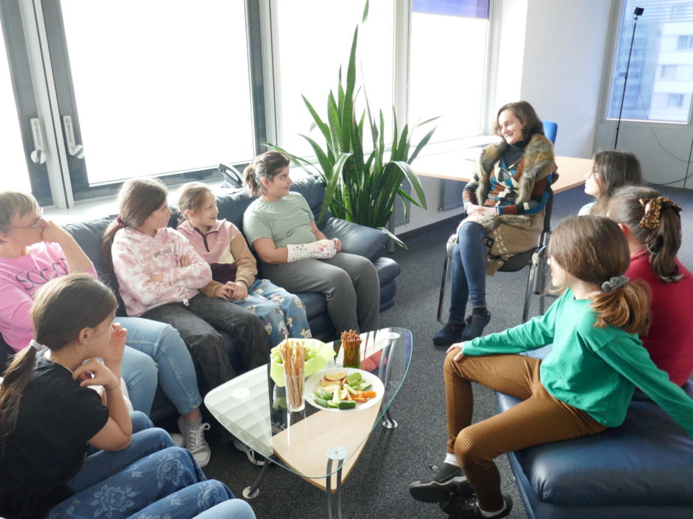 Several girls sit in a circle listening to VRVis researcher Rebecca Nowak.