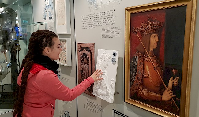 Forscherin Cornelia Travnicek berührt das taktile Relief des VRVis, welches zusammen mit dem berühmten Gemäldes von Maximilian I. bei der Niederösterreichischen Landesausstellung 2019 ausgestellt wurde.