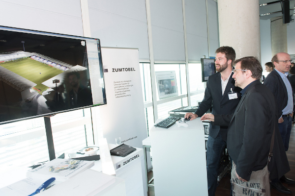 Ein Mitarbeiter des VRVis stellt bei der Leistungsschau ein aktuelles Projekt zur Lichtsimulation vor: zwei Männer schauen auf einen Bildschirm.