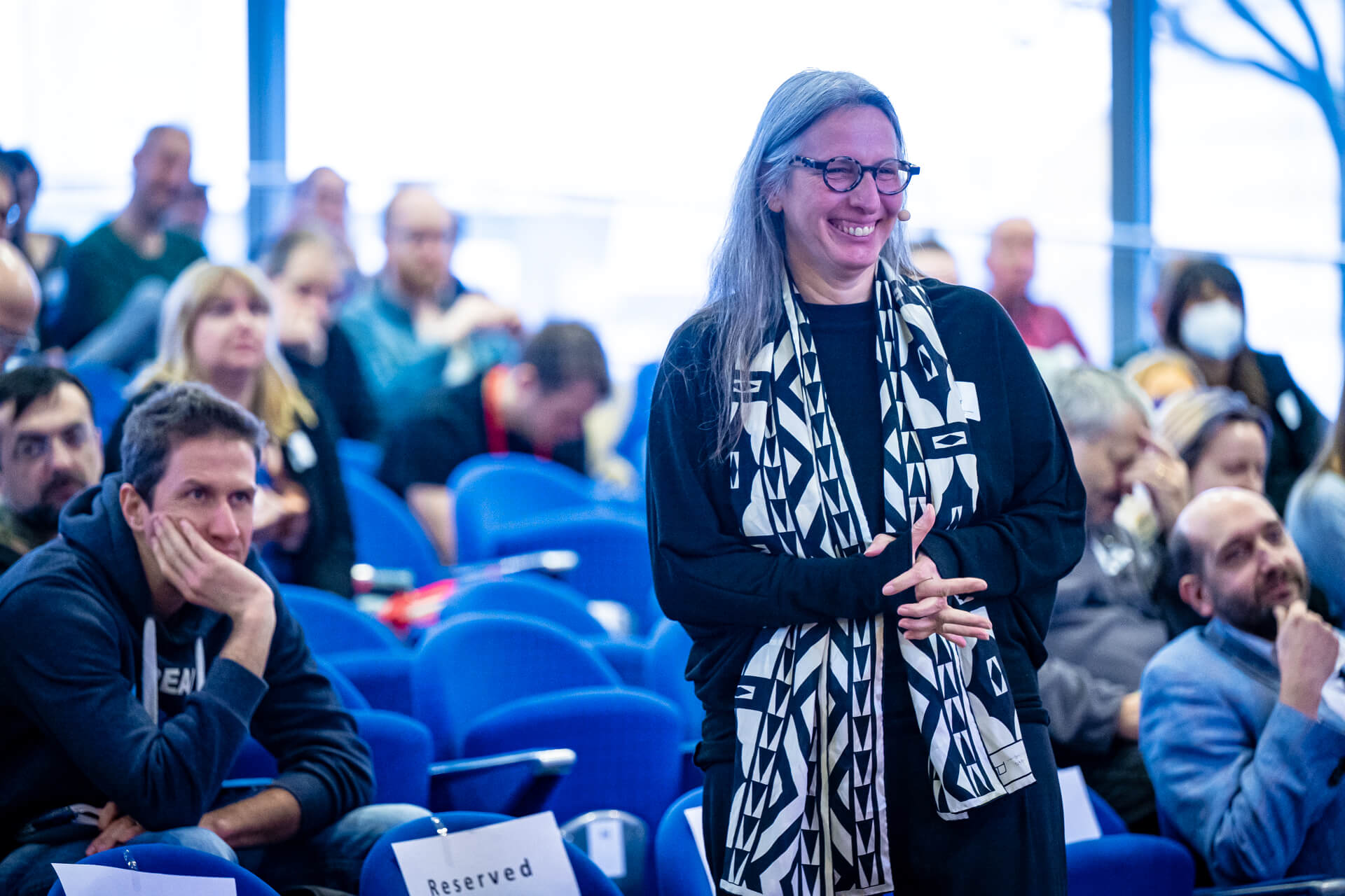 A researcher stands smiling in front of an audience. 