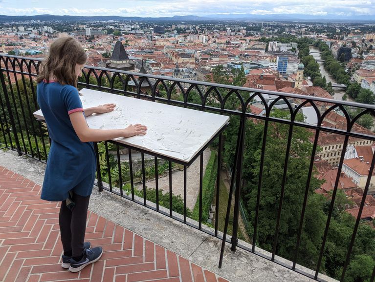 Ein Mädchen ertastet das taktile Panorama-Relief der Stadt Graz