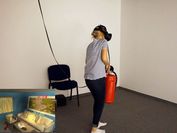 Junge Frau mit einem Feuerlöscher übt in einer VR-Applikation, wie man Feuer richtig löscht. 