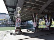 Bridge pier at the Donaukanal, covered with graffiti, the river flows in the background