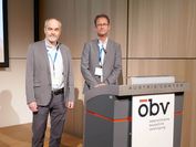 Two researchers in front of a presentation podium at the Baukongress 2022. 