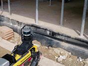 Boston Dynamics-Roboterhund Spot beim Einsatz auf der Baustelle mit Blick auf eine Reihe von Gebäudestützen. 