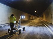 Ein Mann steht mit einem Tunnelvermessungsgerät, das leuchtet, in einem Tunnel, um diesen zu vermessen.