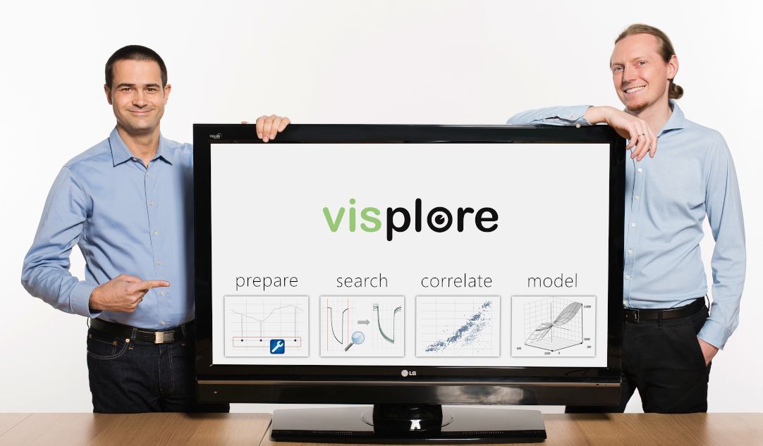 Zwei Männer stehen neben einem Fernsehbildschirm, auf dem groß das Visplore-Logo prangt. 