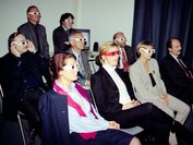 Mehrere Menschen sitzen in einem Raum und haben 3D-Brillen auf und folgen einer Technologie-emo.