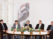 Vier Männer und eine Frau sitzen bei einer Pressekonferenz um einen Tisch und beantworten Fragen.