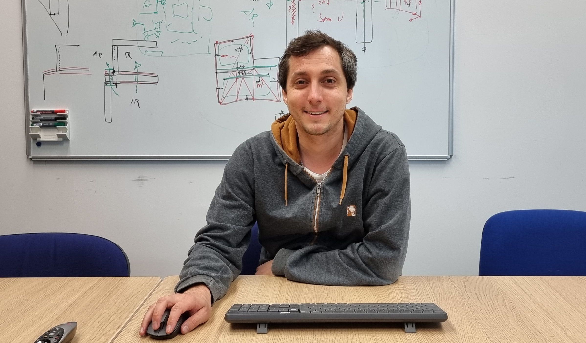 Ein Forscher sitzt vor einer Tastatur und hält die Computermaus in der Hand